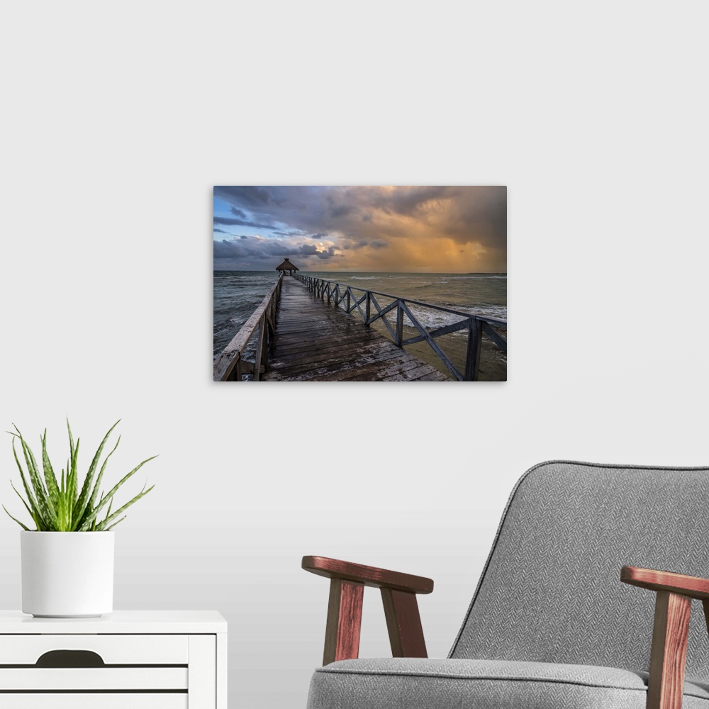 A modern room featuring Photograph of a dock over the ocean with an orange cloudy sunset.