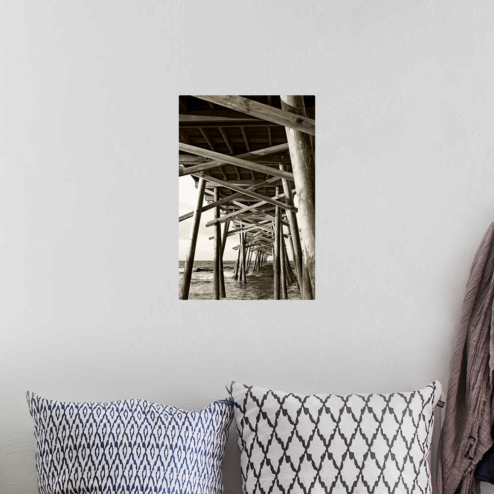 A bohemian room featuring Big monochromatic photograph taken from beneath a large wooden pier examines the foundation of it...