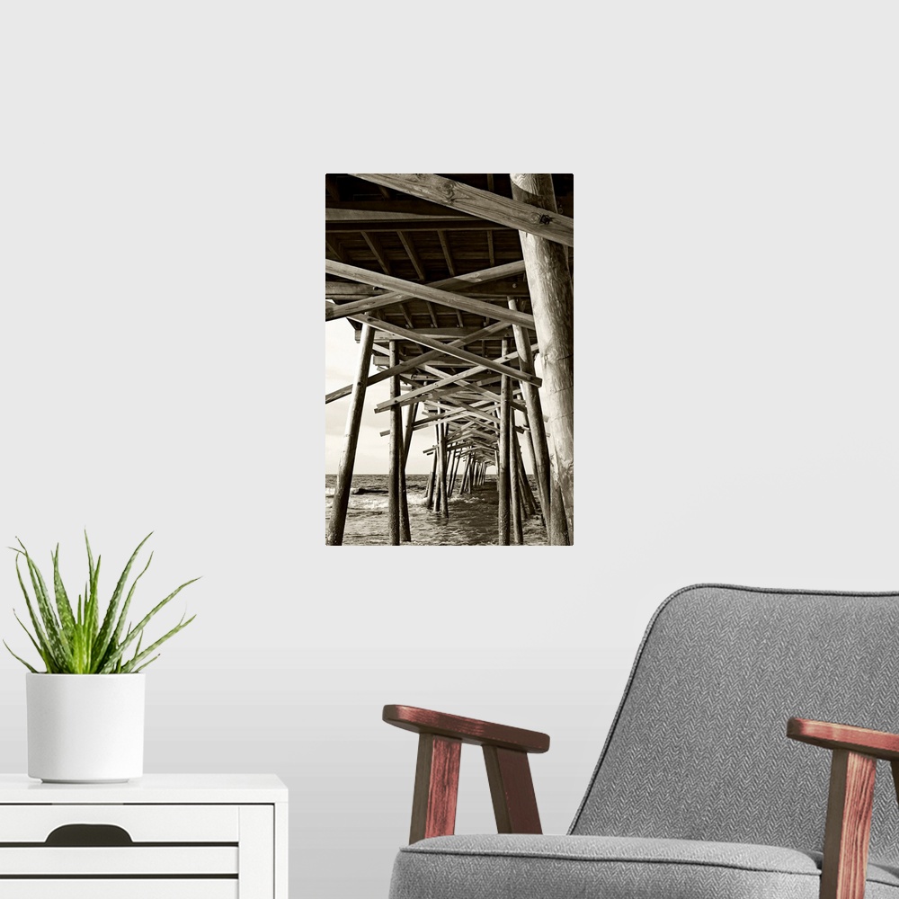 A modern room featuring Big monochromatic photograph taken from beneath a large wooden pier examines the foundation of it...