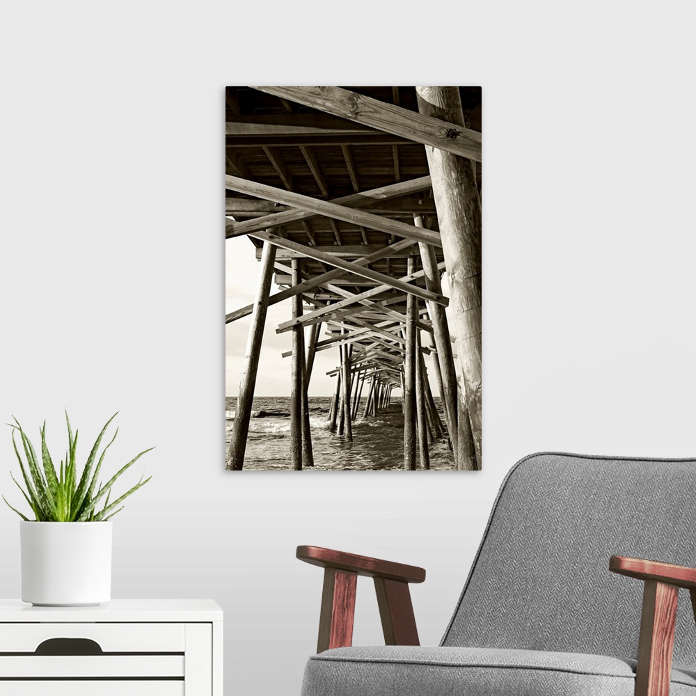 A modern room featuring Big monochromatic photograph taken from beneath a large wooden pier examines the foundation of it...