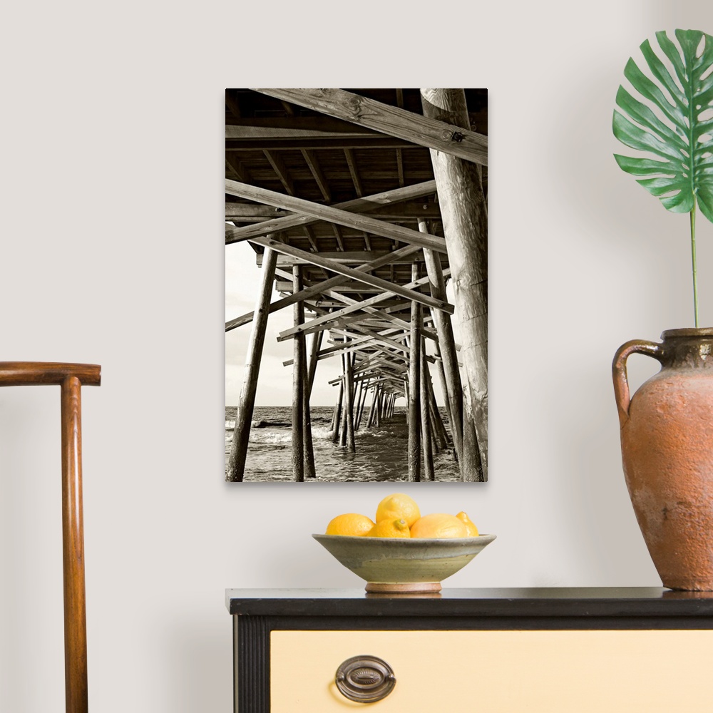 A traditional room featuring Big monochromatic photograph taken from beneath a large wooden pier examines the foundation of it...