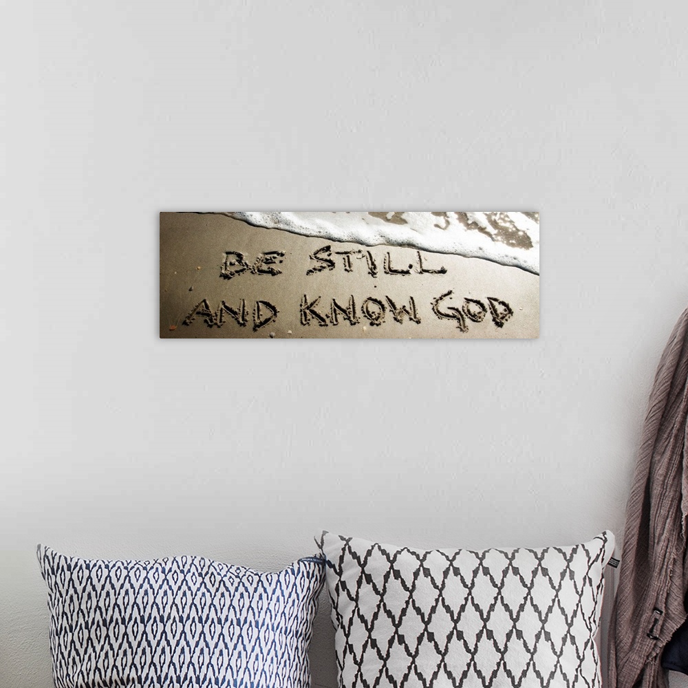 A bohemian room featuring A Bible verse drawn in the sand near the ocean water.