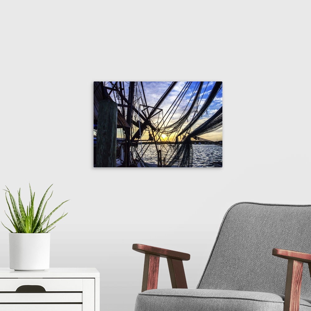 A modern room featuring Photograph of the sunrise though boat lines and nets.