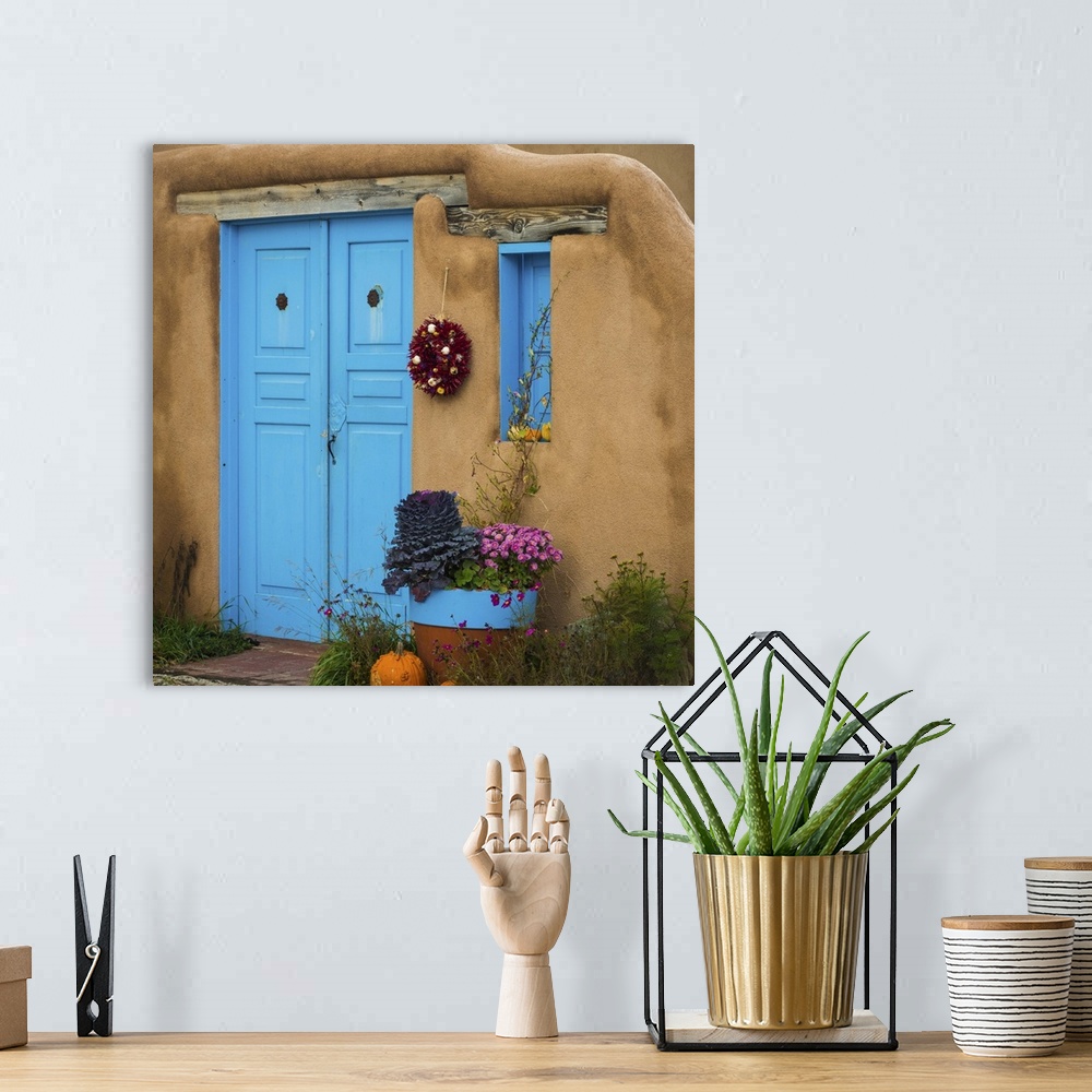 A bohemian room featuring Photograph of a bright blue door and wreath in an adobe wall.
