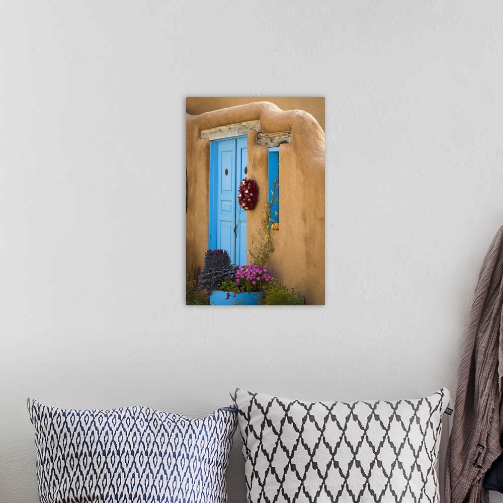 A bohemian room featuring Photograph of a bright blue door and wreath in an adobe wall.