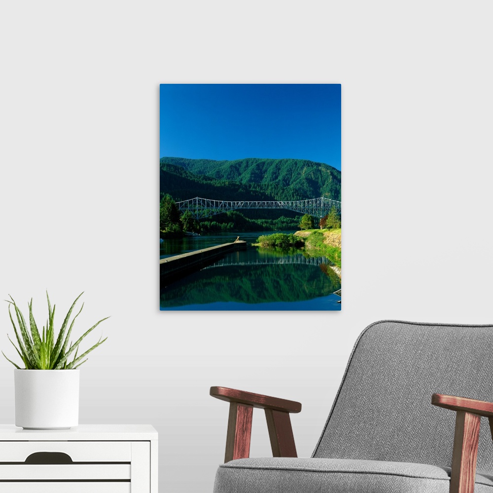 A modern room featuring Photograph of the Columbia river with the Bridge of the Gods going over it and lush mountains in ...