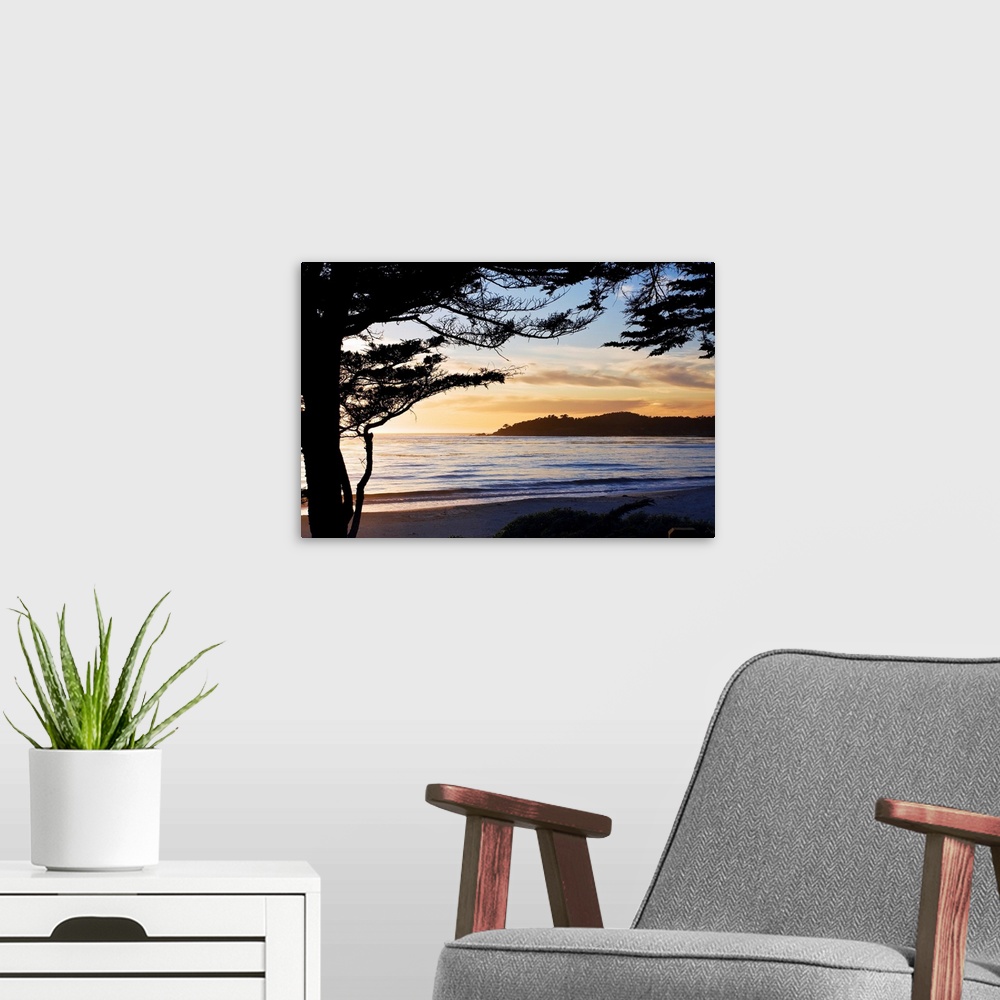 A modern room featuring This landscape photograph of waves rocking against the seashore and the silhouette of a beach pin...