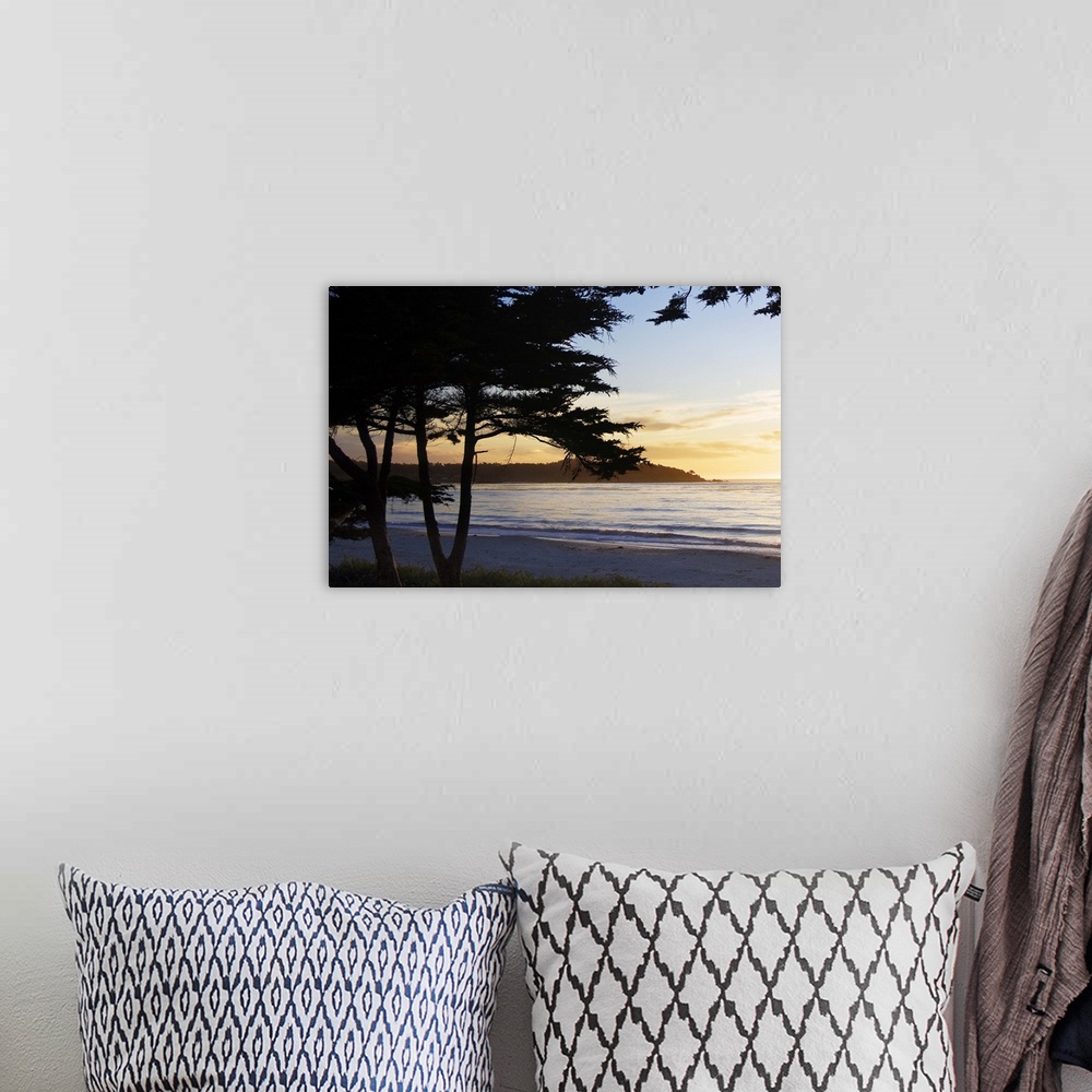 A bohemian room featuring silhouettes of trees in front of an ocean sunset in Carmel, California.