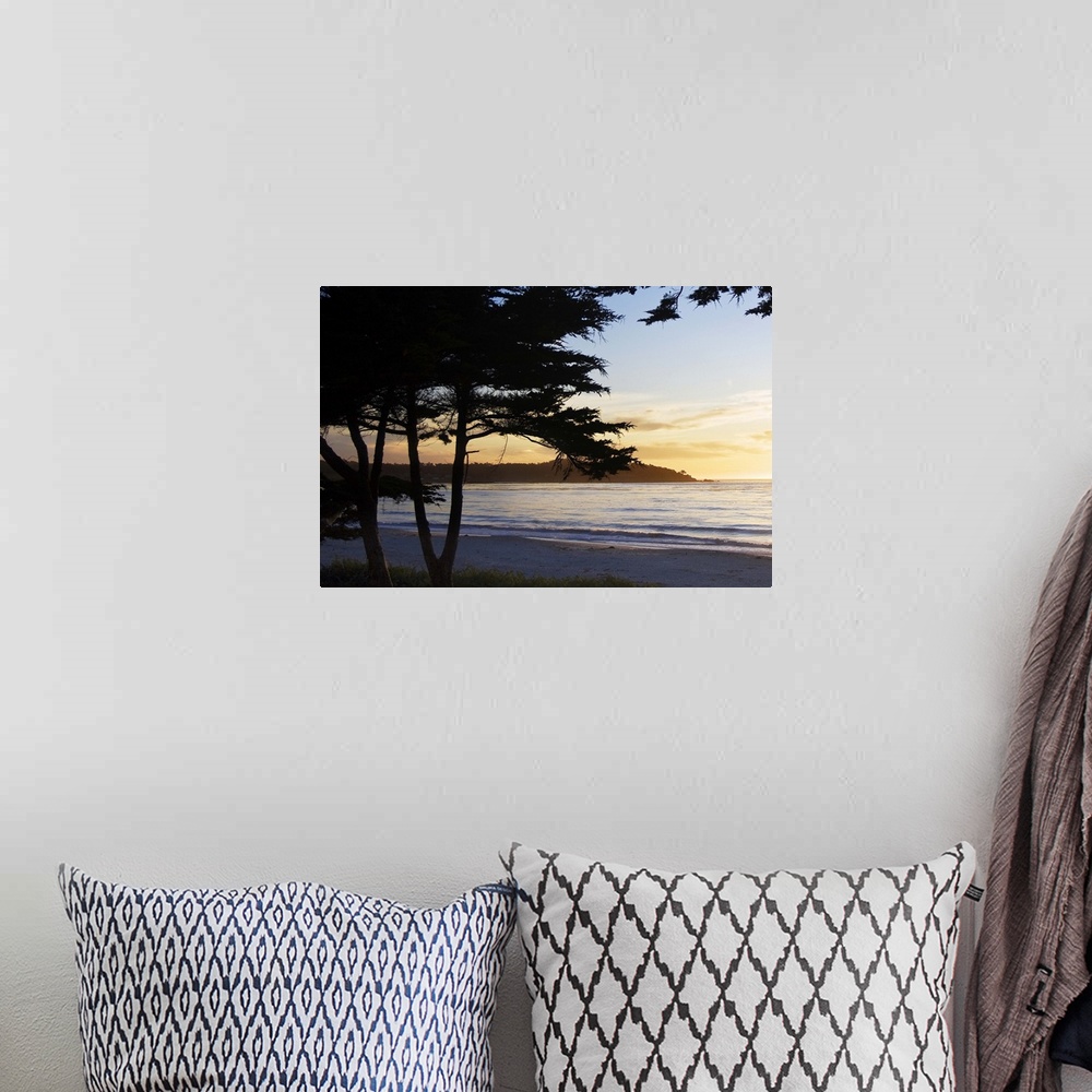A bohemian room featuring silhouettes of trees in front of an ocean sunset in Carmel, California.