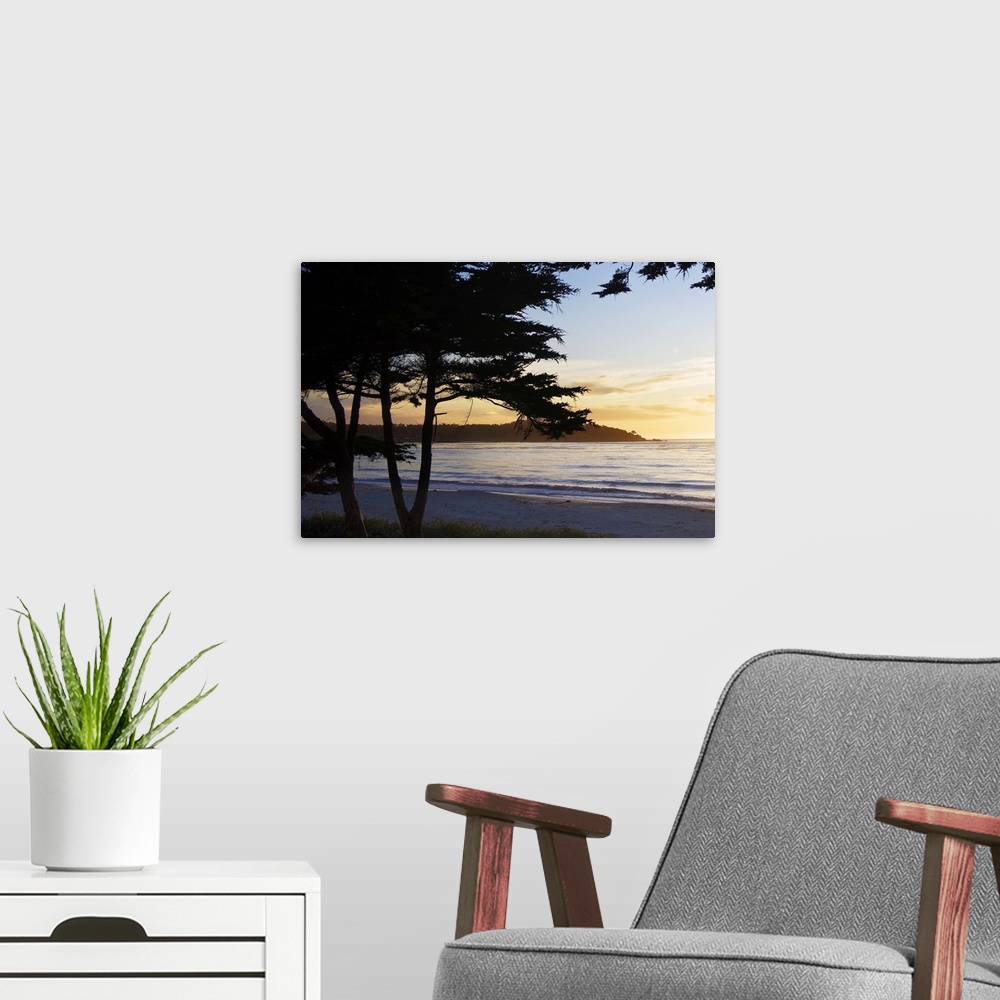 A modern room featuring silhouettes of trees in front of an ocean sunset in Carmel, California.