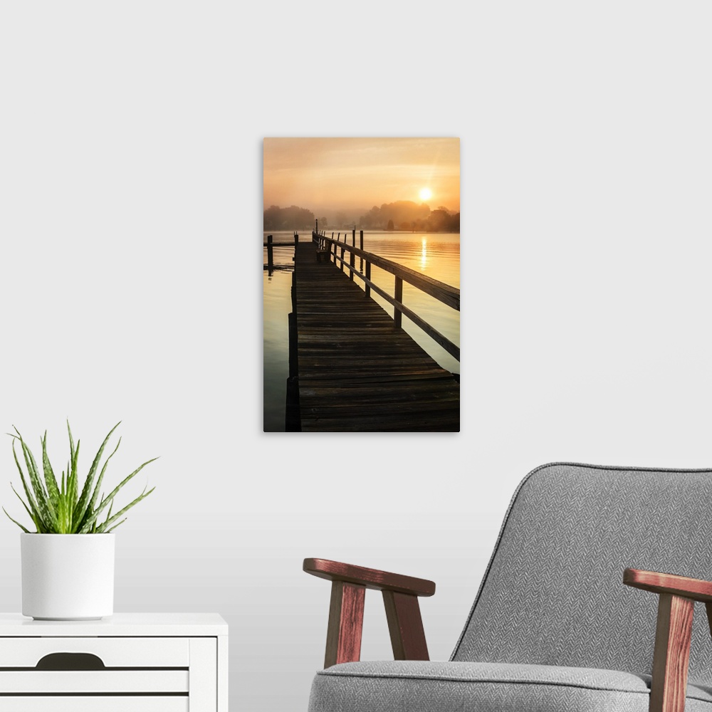 A modern room featuring Silhouetted pier on a calm ocean in orange sunrise light.