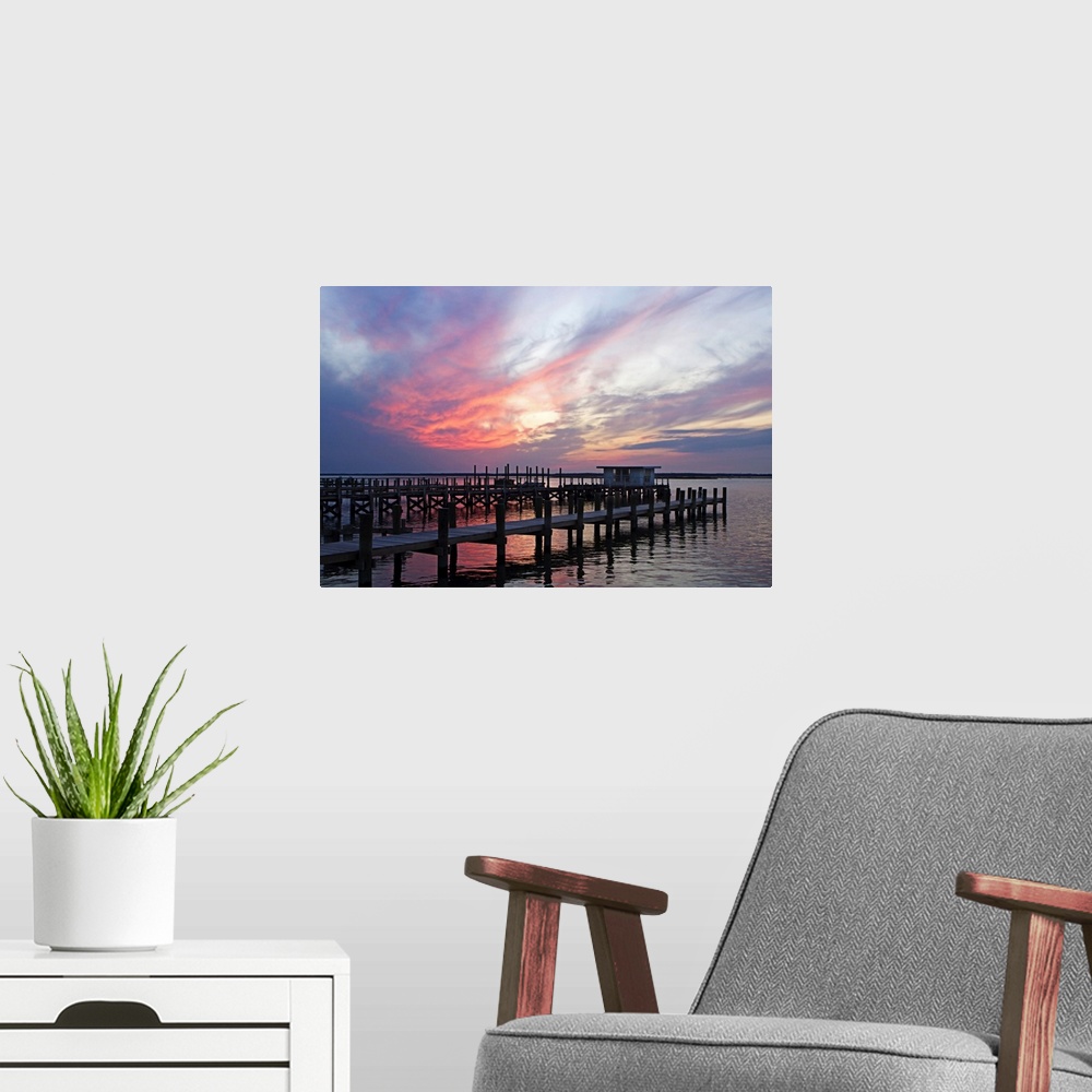 A modern room featuring Landscape photograph on a big wall hanging of several docks lined next to each other, in calm wat...
