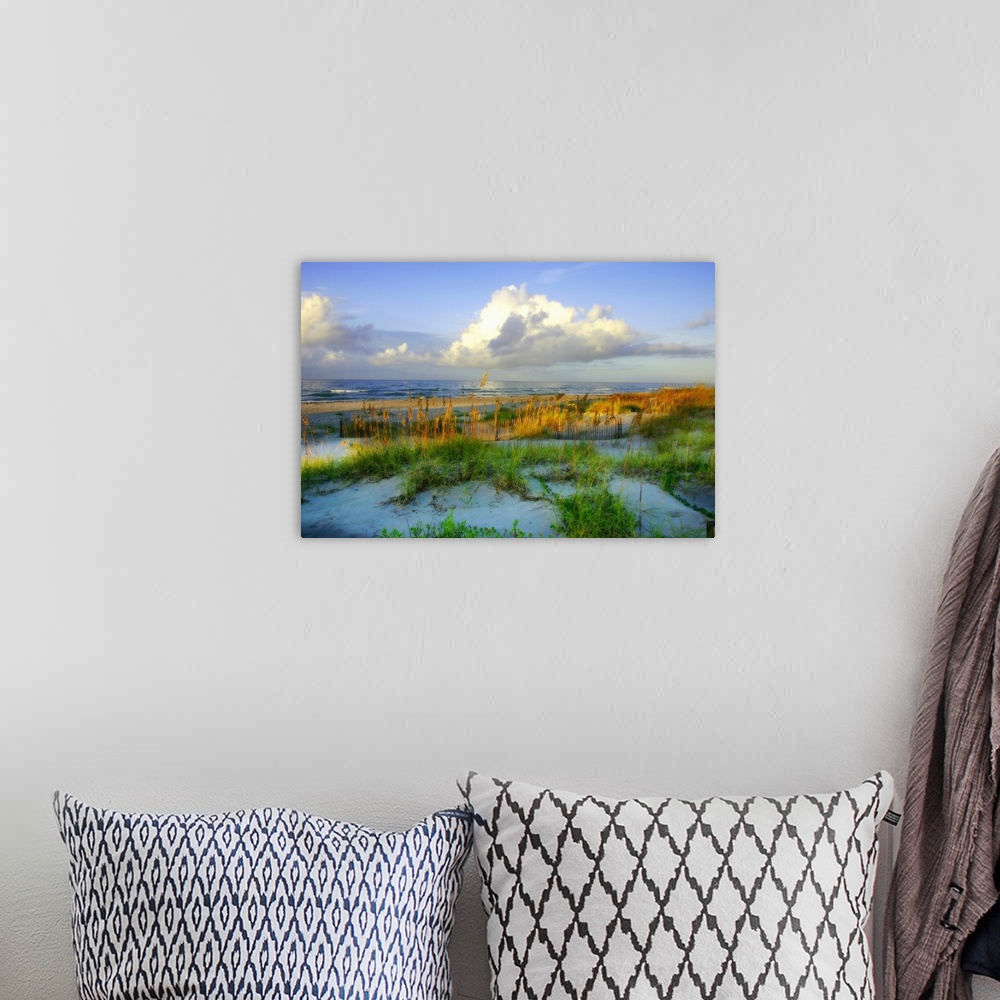 A bohemian room featuring Horizontal, oversized photograph of grassy dunes in front of the shoreline, beneath a blue sky wi...