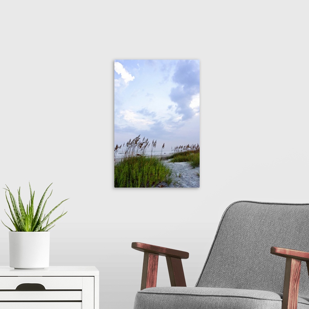 A modern room featuring Vertical photo print of sea grass on dunes with waves crashing onto a beach in the distance.