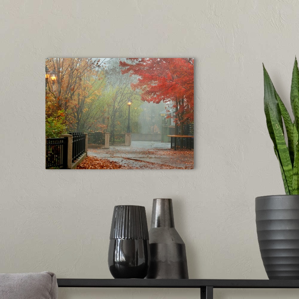 A modern room featuring A photograph of a city walkway covered with autumn leaves on a misty day.