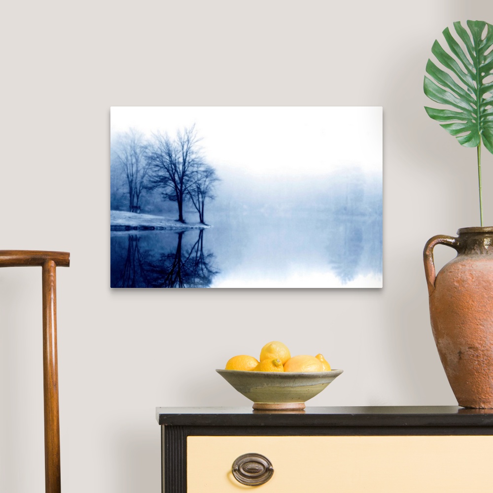 A traditional room featuring A photograph taken of a lake with bare trees off to the left side and more trees behind dense fog...