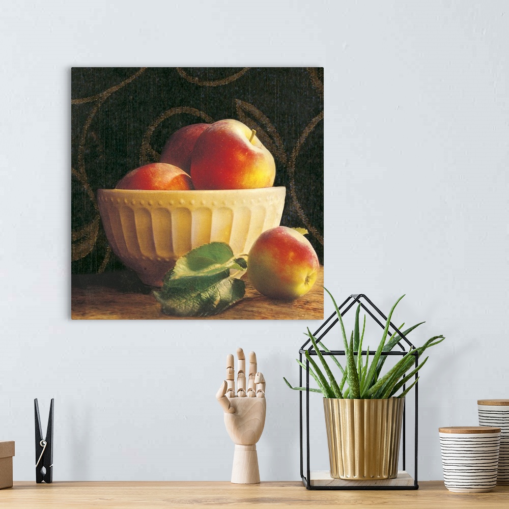 A bohemian room featuring Giant photograph shows a group of three apples sticking out the top of an ornamental bowl on a ta...