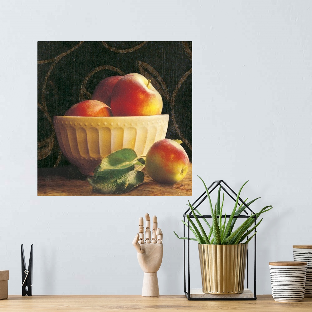A bohemian room featuring Giant photograph shows a group of three apples sticking out the top of an ornamental bowl on a ta...