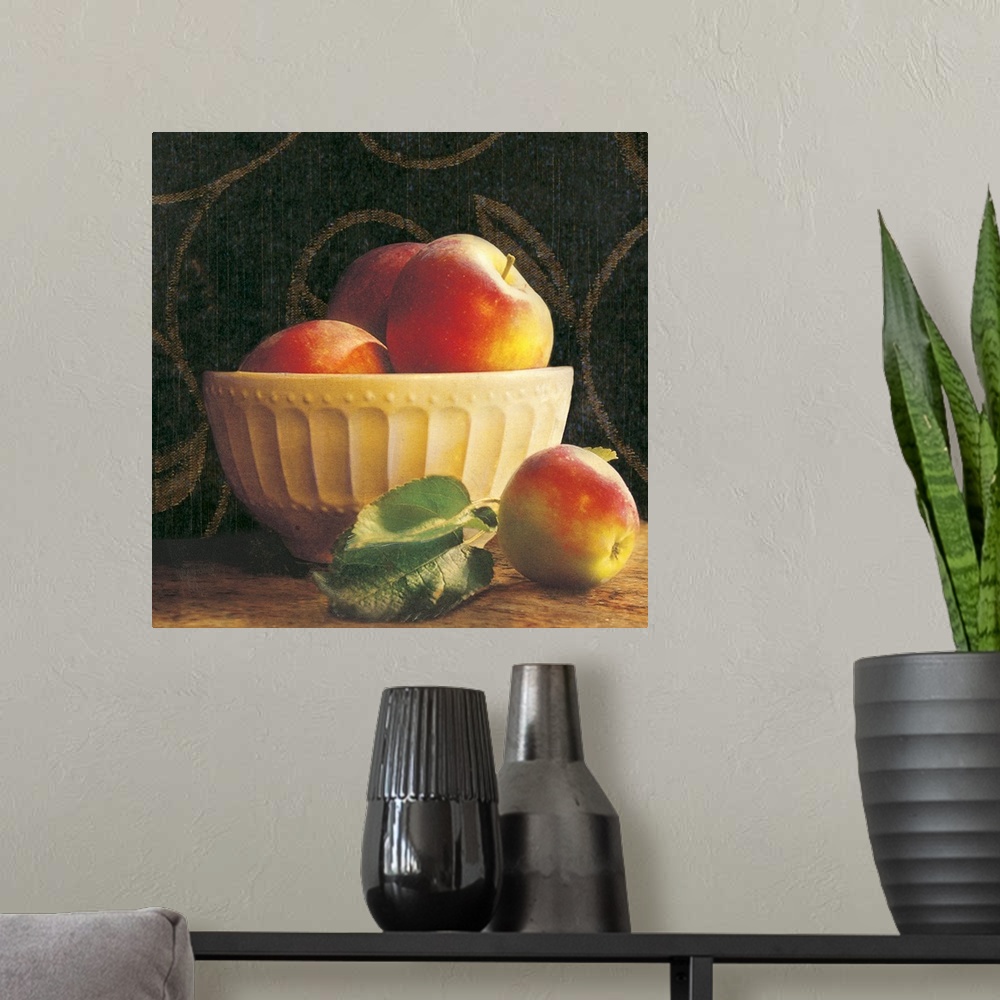 A modern room featuring Giant photograph shows a group of three apples sticking out the top of an ornamental bowl on a ta...