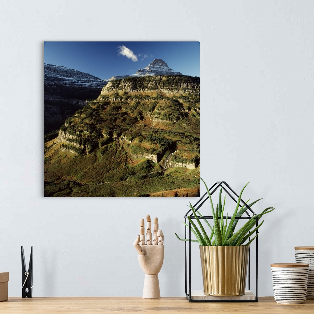 A bohemian room featuring Landscape photograph of sun shining on a mountain side with a snow covered mountain in the backgr...