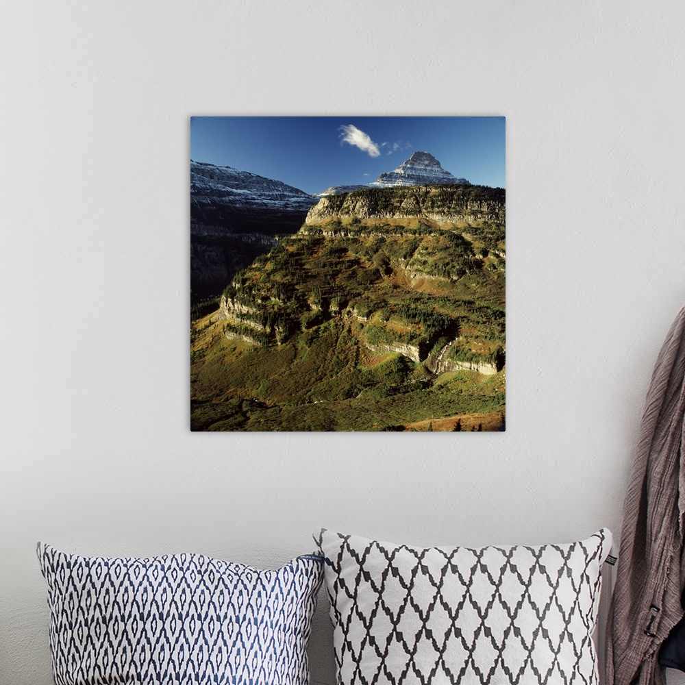 A bohemian room featuring Landscape photograph of sun shining on a mountain side with a snow covered mountain in the backgr...