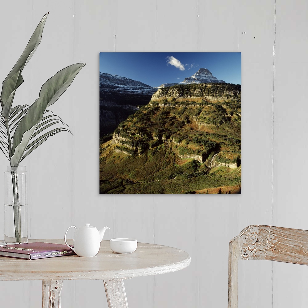 A farmhouse room featuring Landscape photograph of sun shining on a mountain side with a snow covered mountain in the backgr...
