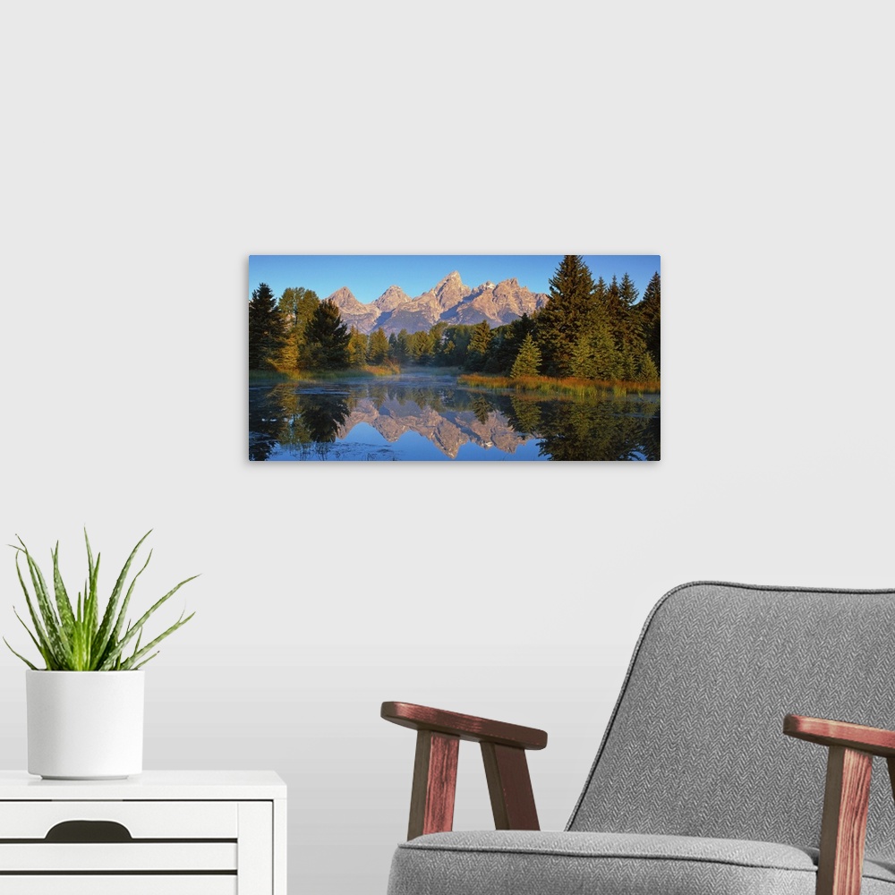 A modern room featuring View of the Grand Teton Mountain range in Wyoming, reflected in a lake.