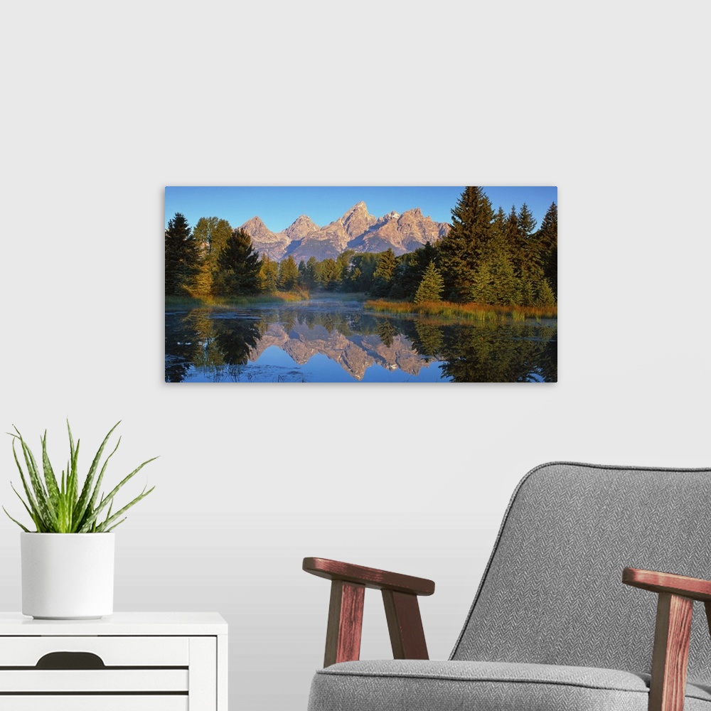 A modern room featuring View of the Grand Teton Mountain range in Wyoming, reflected in a lake.