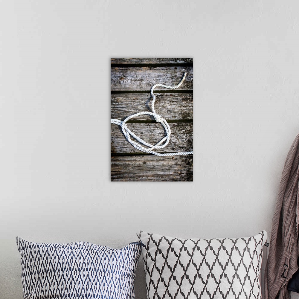 A bohemian room featuring Photograph of a white rope looped and tied with a knot on a wooden background.
