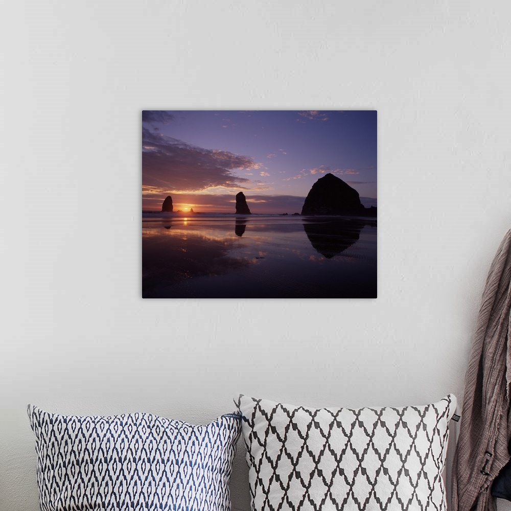 A bohemian room featuring Silhouetted photograph of Haystack Rock during a purple and orange sunset.