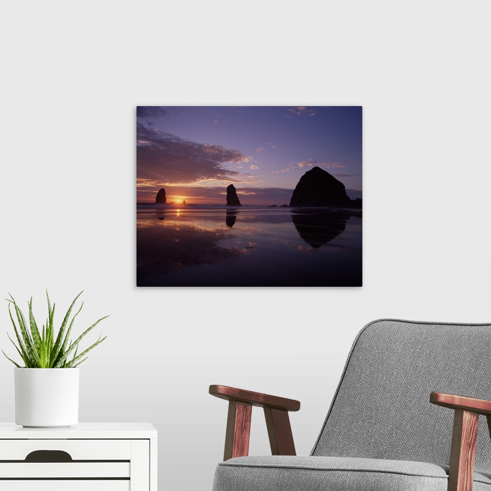 A modern room featuring Silhouetted photograph of Haystack Rock during a purple and orange sunset.