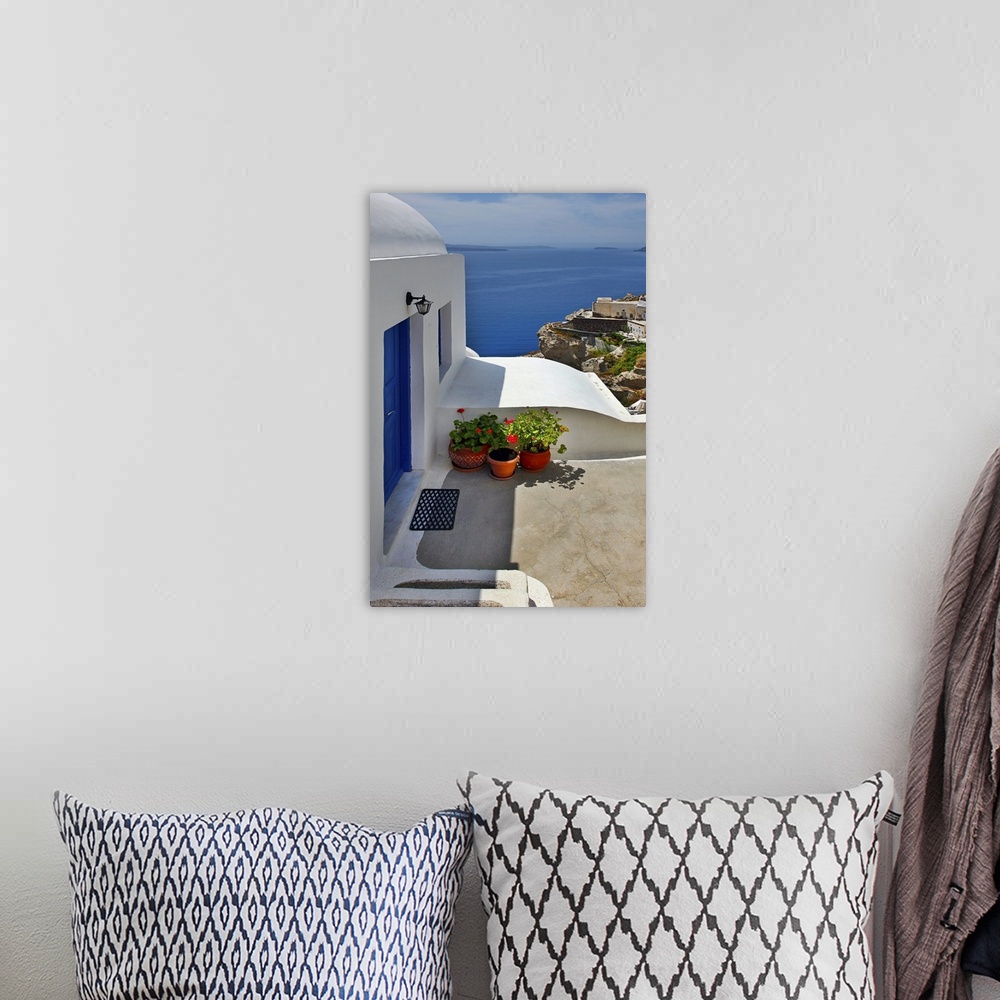 A bohemian room featuring Vertical photo of home with blue door and ocean view in the village of Oia on the island of Santo...