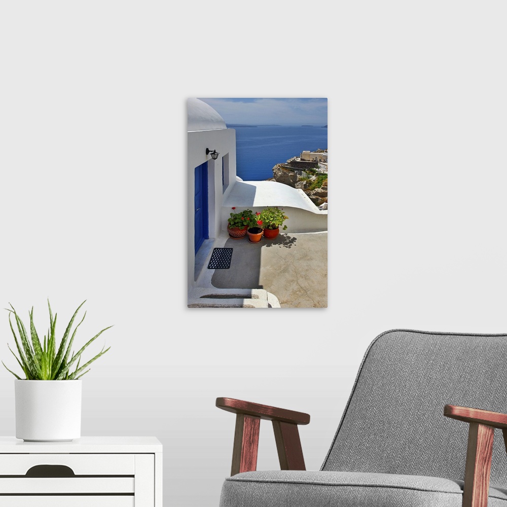 A modern room featuring Vertical photo of home with blue door and ocean view in the village of Oia on the island of Santo...