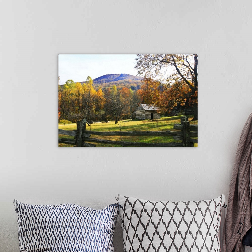 A bohemian room featuring This is a landscape photograph of a log cabin in a meadow surrounded by autumn trees behind a pri...