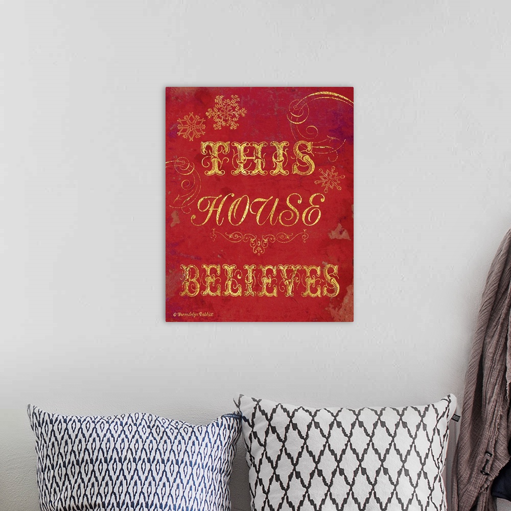 A bohemian room featuring Holiday decor in red and gold that reads "This House Believes"