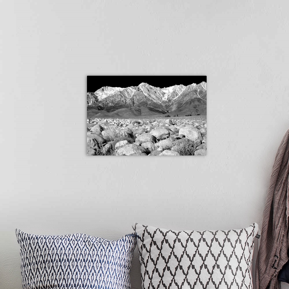 A bohemian room featuring Black and white photograph of rock covered ground leading to snowy mountain peaks in the background.