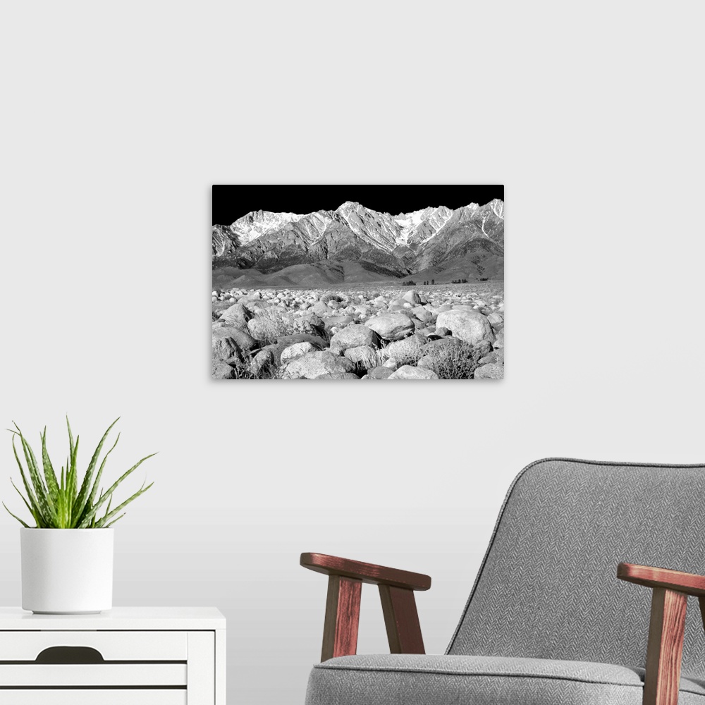A modern room featuring Black and white photograph of rock covered ground leading to snowy mountain peaks in the background.