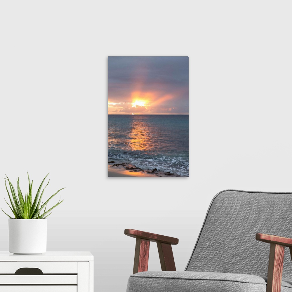 A modern room featuring Vertical photograph of a sunset beaming though clouds over a blue ocean.