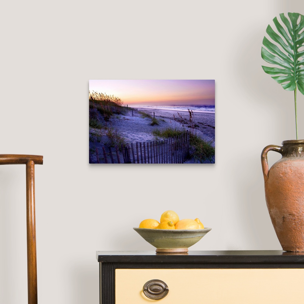 A traditional room featuring A landscape photograph of a dune covered in sea grass and fences fills the foreground of this bea...