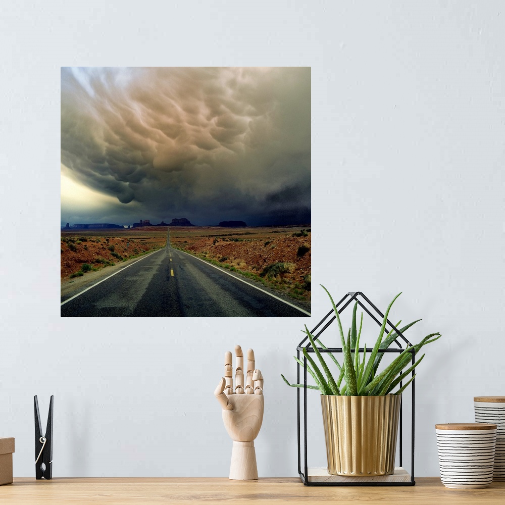 A bohemian room featuring Heavy storm clouds over a road through the desert in Monument Valley.