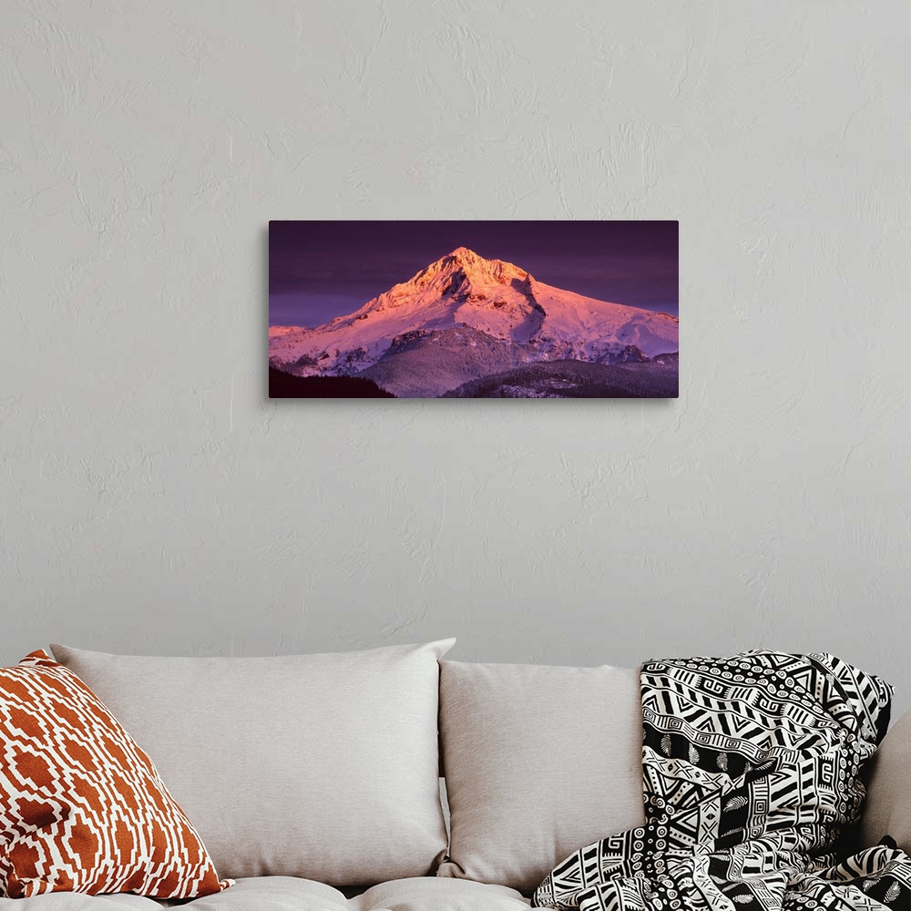 A bohemian room featuring Mount Hood illuminated in sunset colors at dusk.