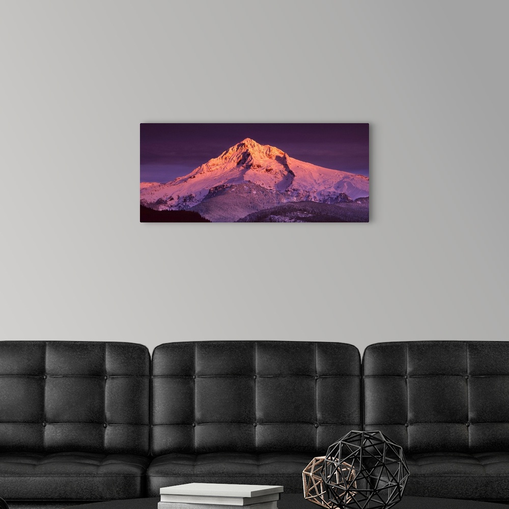 A modern room featuring Mount Hood illuminated in sunset colors at dusk.