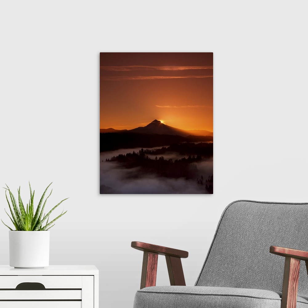 A modern room featuring The sun setting behind Mount Hood, with dense fog in the valley below.