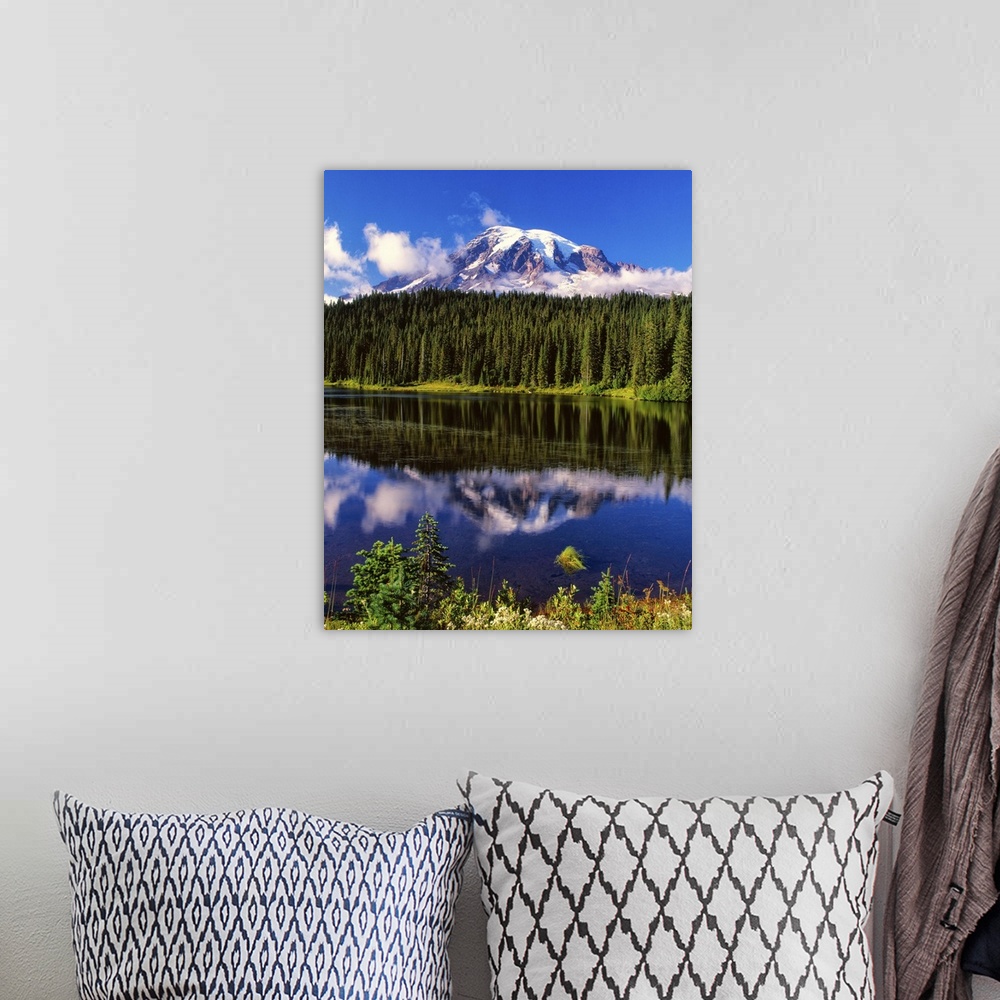 A bohemian room featuring Mount Rainier surrounded by clouds seen from a lake.
