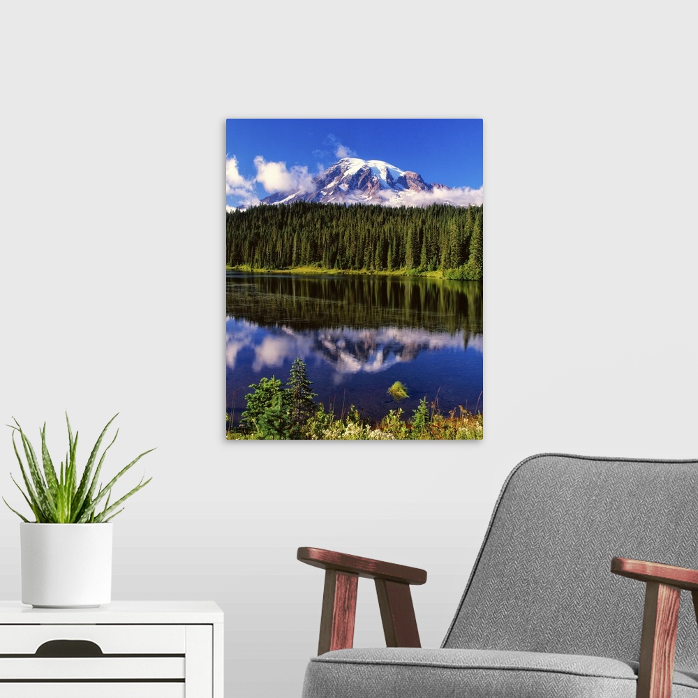 A modern room featuring Mount Rainier surrounded by clouds seen from a lake.