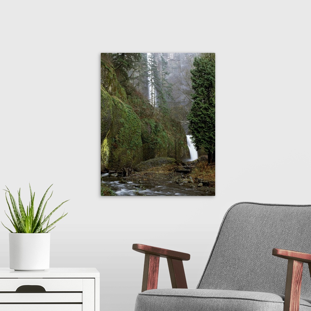 A modern room featuring Landscape photograph of the Multnomah Falls from a creek side view.
