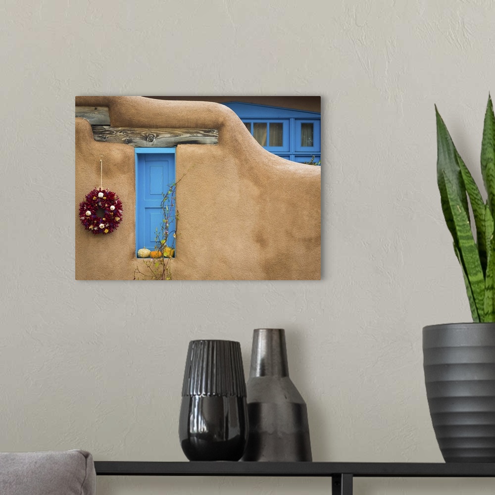 A modern room featuring Photograph of a bright blue door and wreath in an adobe wall.