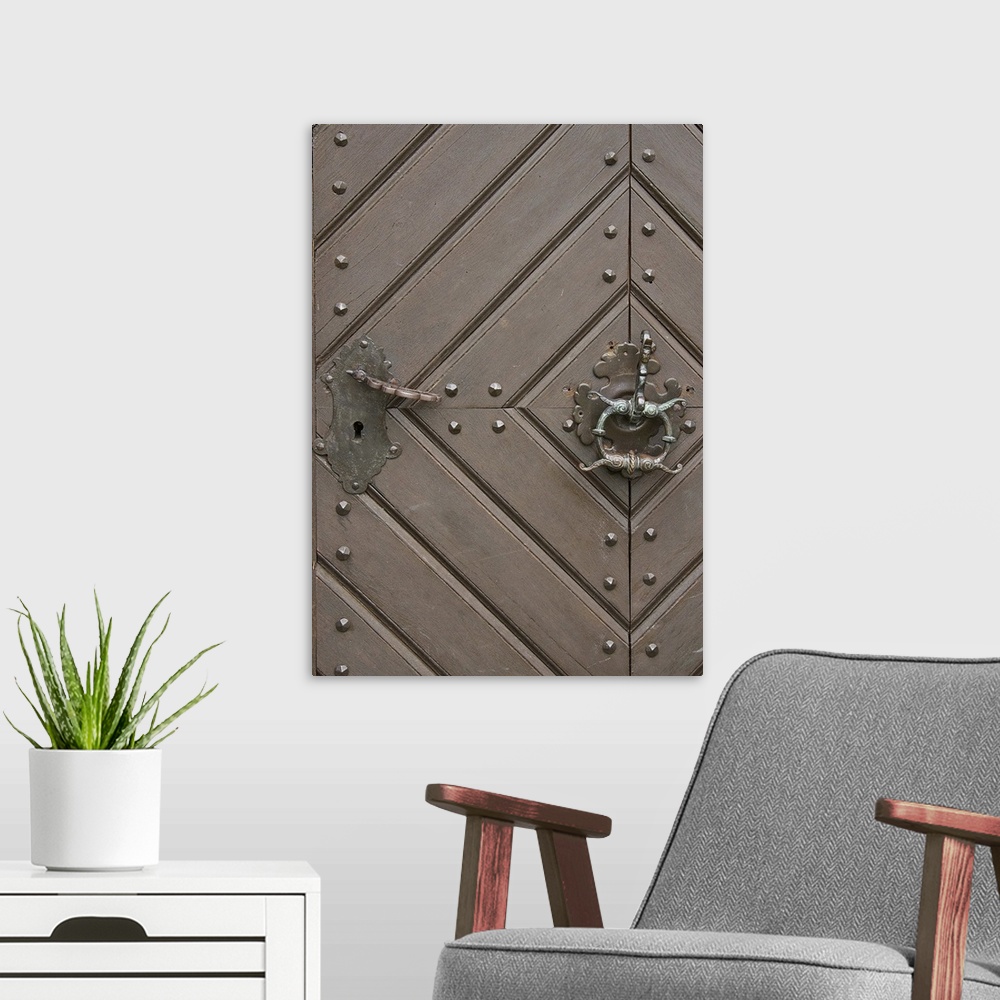A modern room featuring Close up of a wooden door with a diamond pattern and an iron knocker.