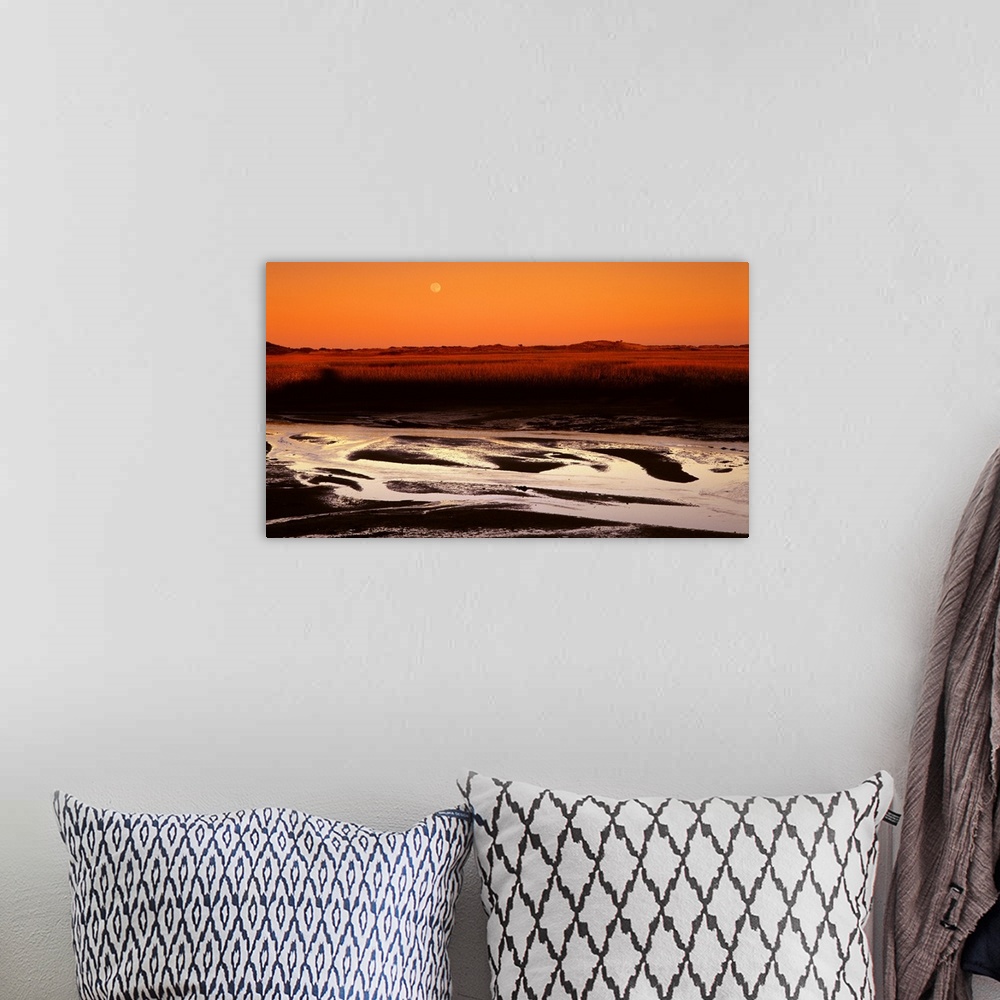 A bohemian room featuring Landscape photograph with an orange sunset and a full moon in the sky.