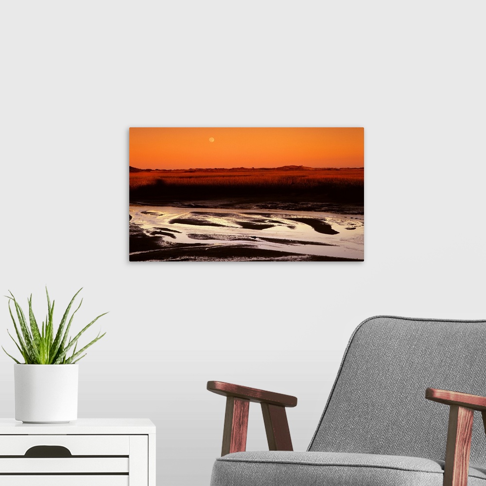 A modern room featuring Landscape photograph with an orange sunset and a full moon in the sky.